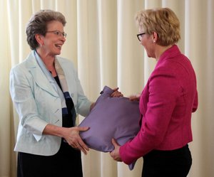 Oberbürgermeisterin Barbara Bosch überreicht Direktorin Gabriele Beier ein fliederfarbenes Kissen als Gastgeschenk zum Jubiläum der Evangelischen Fachschule für Sozialpädagogik Reutlingen.